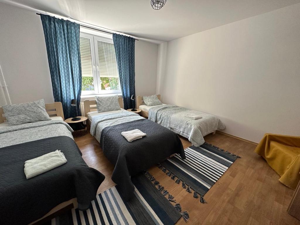 Cette chambre comprend 3 lits et une fenêtre. dans l'établissement Mirabella House, à Rzeszów