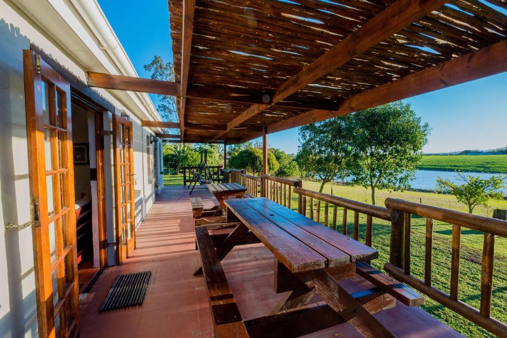 eine hölzerne Veranda mit Bänken an der Seite eines Hauses in der Unterkunft Boscia Farmstay in George