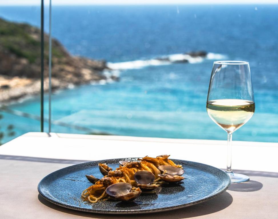a plate of food next to a glass of wine at Hotel Baia Imperiale in Campo nell'Elba