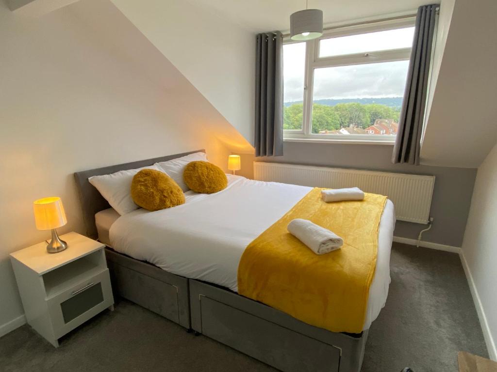 a bedroom with a bed with a yellow blanket and a window at Cosy room Maidstone in Kent