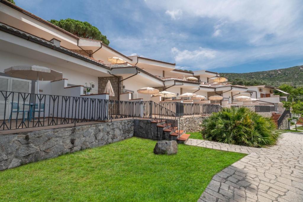 a house with a fence with umbrellas in a yard at Hotel Baia Imperiale in Campo nell'Elba