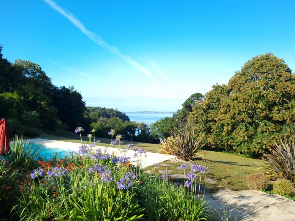 a garden with purple flowers and a view of the water at Domaine de Stang Bihan in Concarneau