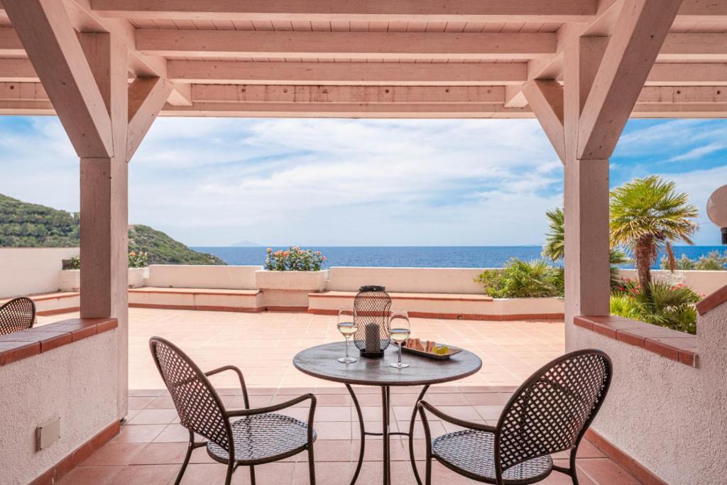 a patio with a table and chairs and the ocean at Hotel Baia Imperiale in Campo nell'Elba