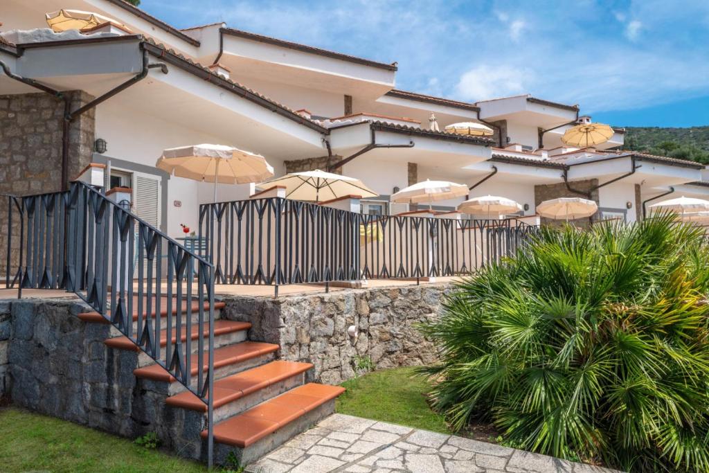 a house with a fence and stairs with umbrellas at Hotel Baia Imperiale in Campo nell'Elba