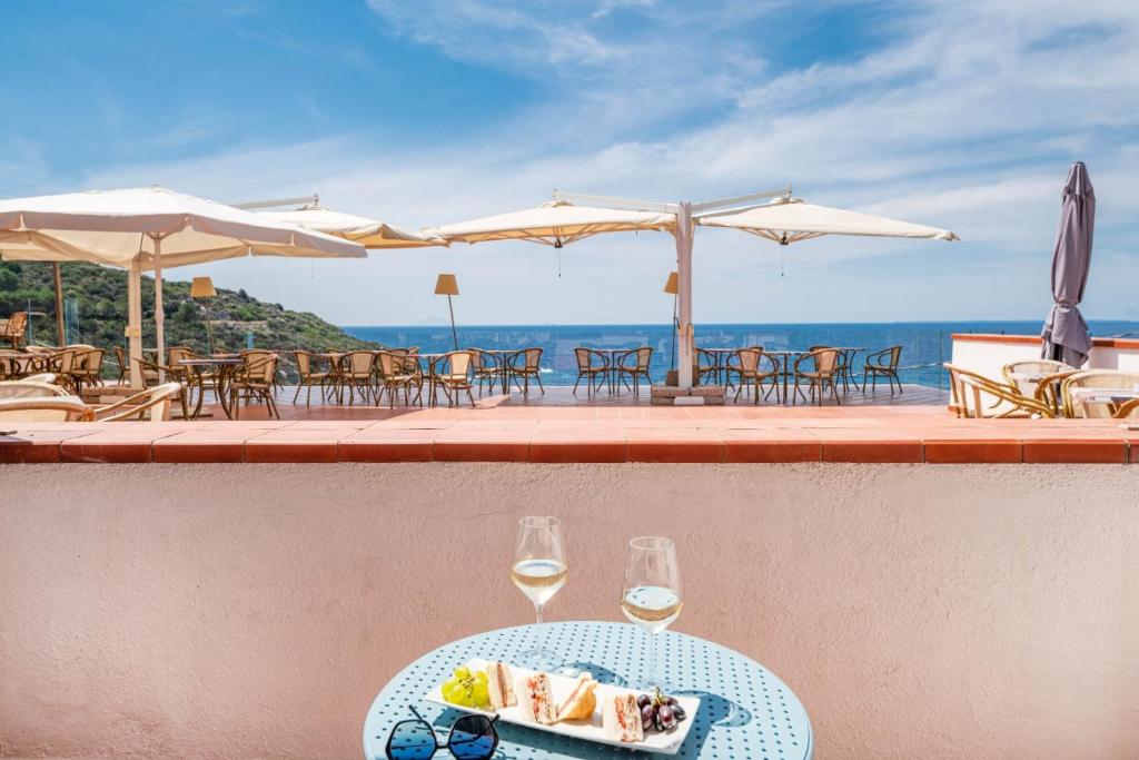a table with a plate of food and two glasses of wine at Hotel Baia Imperiale in Campo nell'Elba