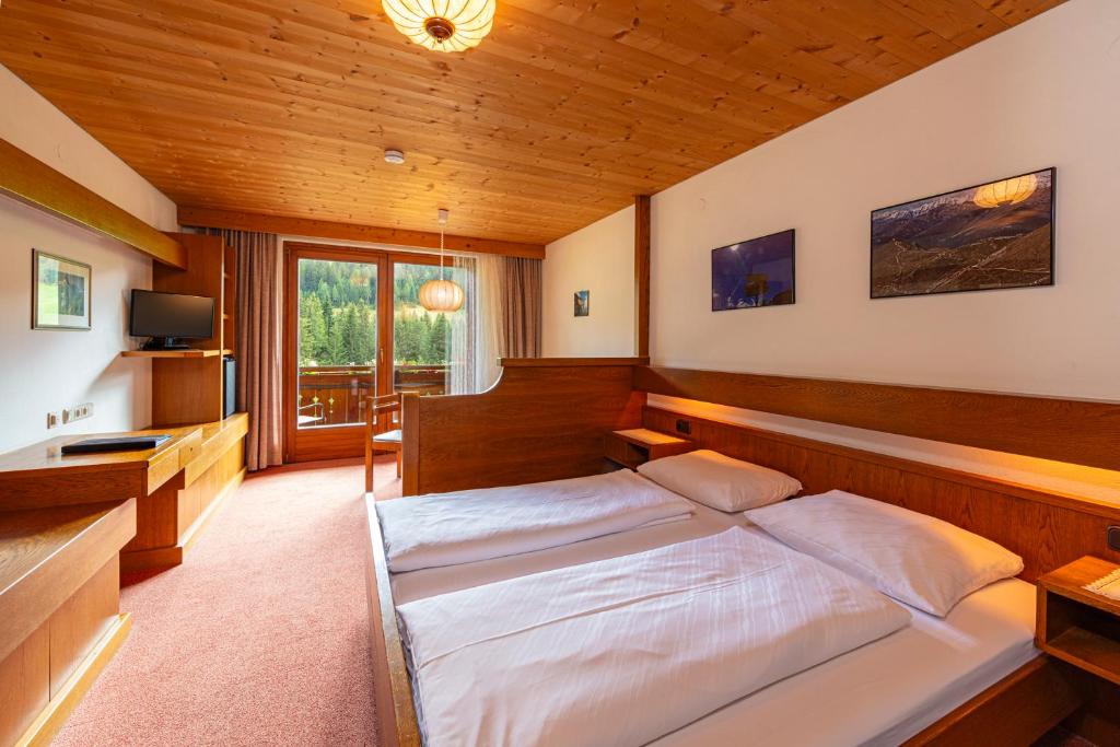 a bedroom with a bed and a desk in it at Panorama Hotel CIS - bed and breakfast in Kartitsch