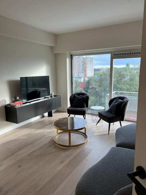 un soggiorno con sedie, TV e tavolo di Luxury Apartment in Berchem-Antwer ad Anversa