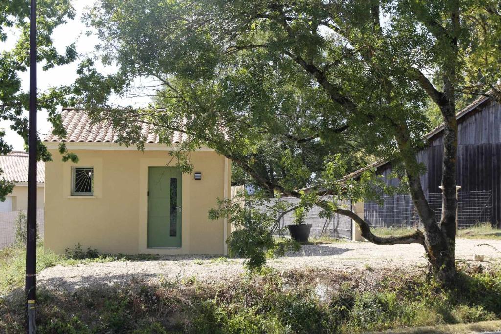 una casa con una puerta verde y un árbol en Maisonnette neuve Monbazillac en Monbazillac