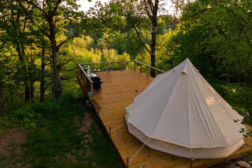 a tent on a wooden boardwalk in the woods at Glamping Žvaigždžių slėnyje 