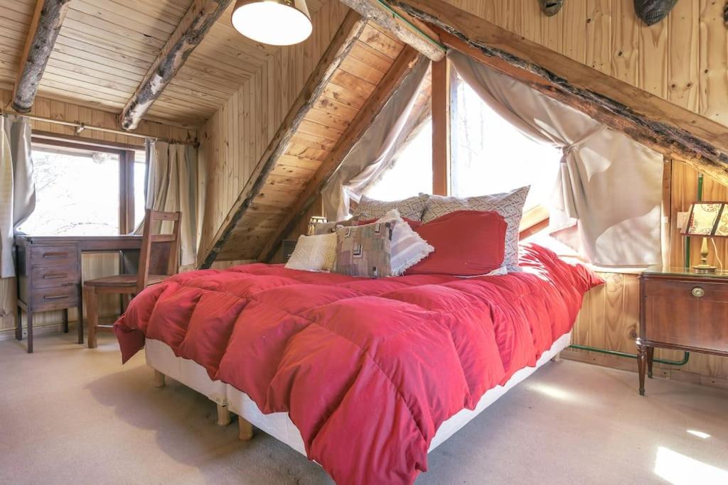 a bedroom with a large red bed with a window at Pai Pay Calido y Confortable Bungalow in San Carlos de Bariloche