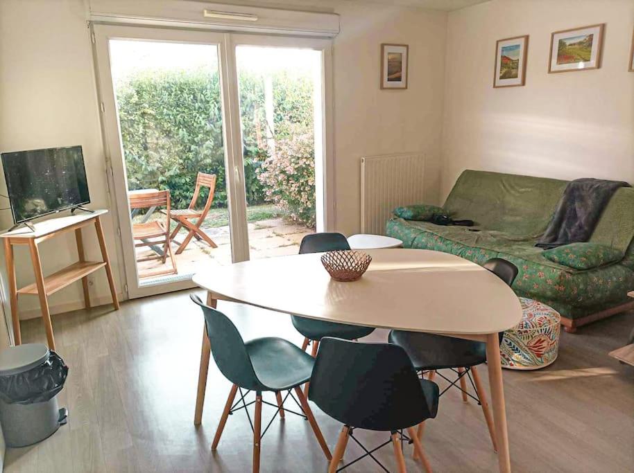 un soggiorno con tavolo, sedie e divano di Studio le Flamboyant a Cholet