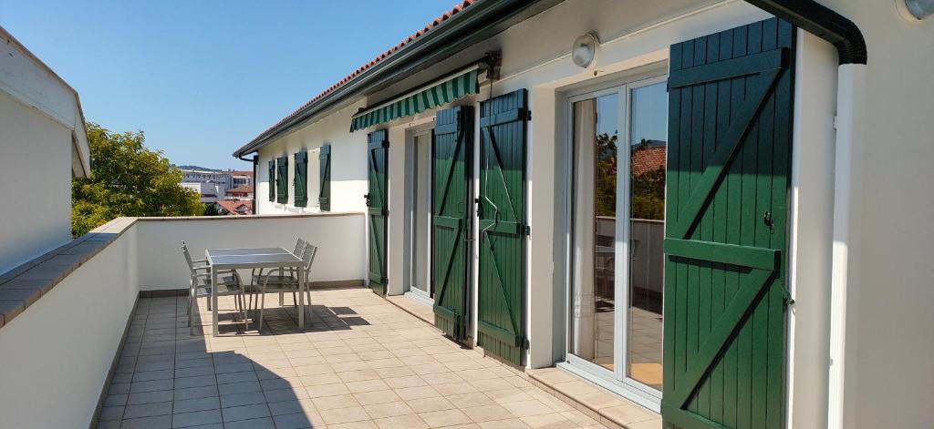 un patio avec des portes vertes et une table sur un balcon dans l'établissement Relax, silencio y sol en el jardin, à Hendaye