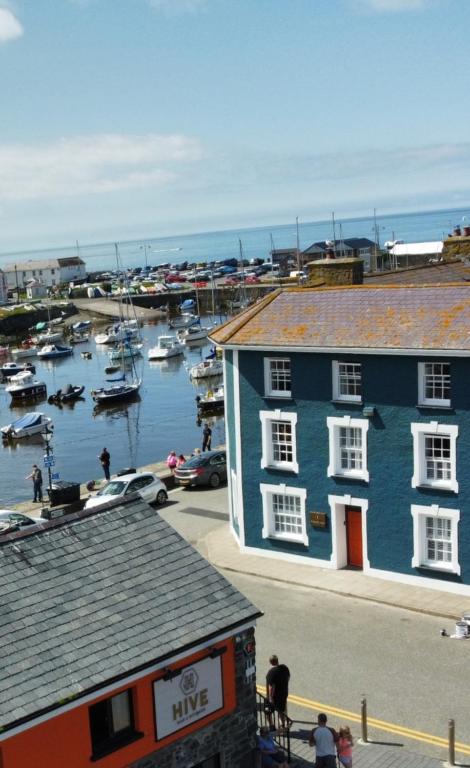 un edificio azul junto a un puerto deportivo con barcos en el agua en Hive Townhouse, en Aberaeron