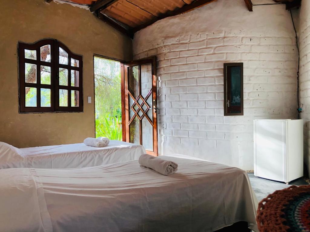 1 dormitorio con 2 camas y nevera en Espaço Shanti - Chalés en Sao Jorge