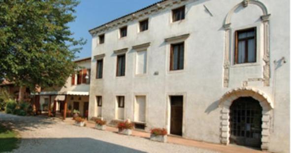 a large white building with an archway in front of it at Agriturismo Il Palazzone in Montegalda