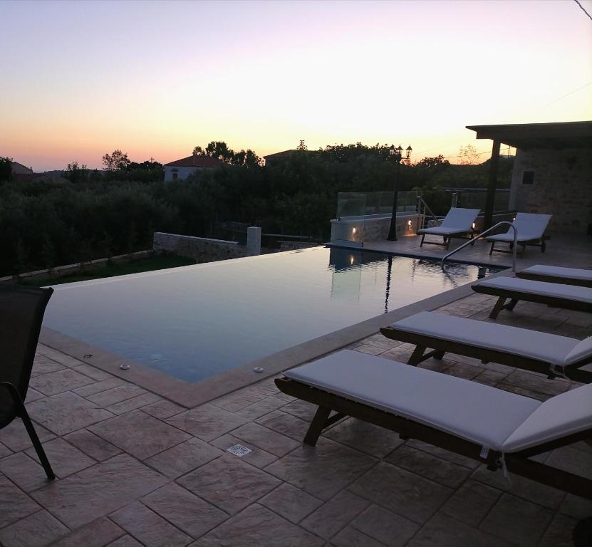 a swimming pool with lounge chairs on a patio at VILLA HALEPOURI in Chania