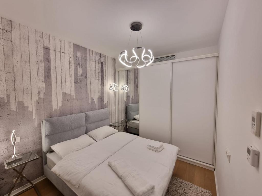 sypialnia z białym łóżkiem i żyrandolem w obiekcie One Inclusive Best Region Apartment w Bukareszcie