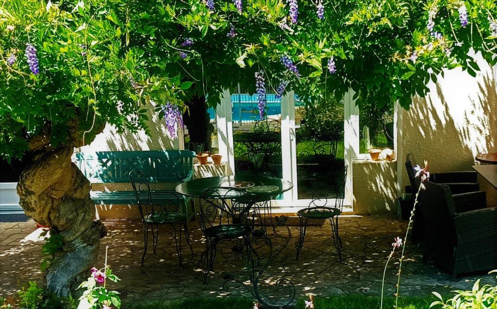 a patio with a table and chairs under a tree at Villa Lortin in Pouillon