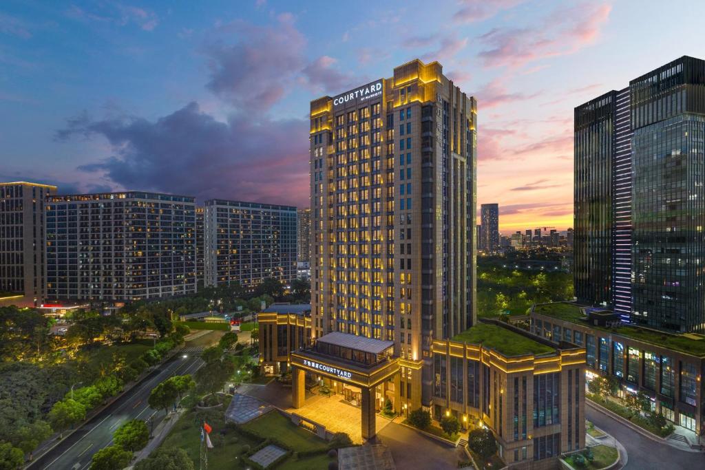 a tall building with a green roof in a city at Courtyard by Marriott Hangzhou Xiaoshan in Hangzhou