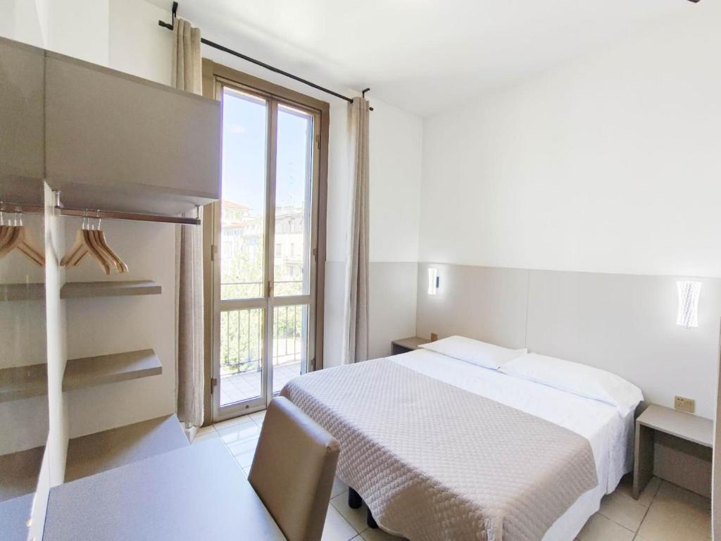 a white bedroom with a bed and a window at Hotel Mondial in Milan