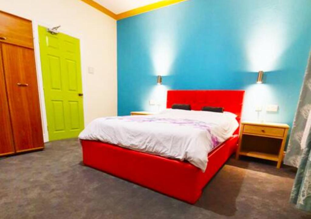 a bedroom with a red bed and a green door at Modern En-suite Doubles near Boston Town: Spacious & Contemporary Rooms in Lincolnshire