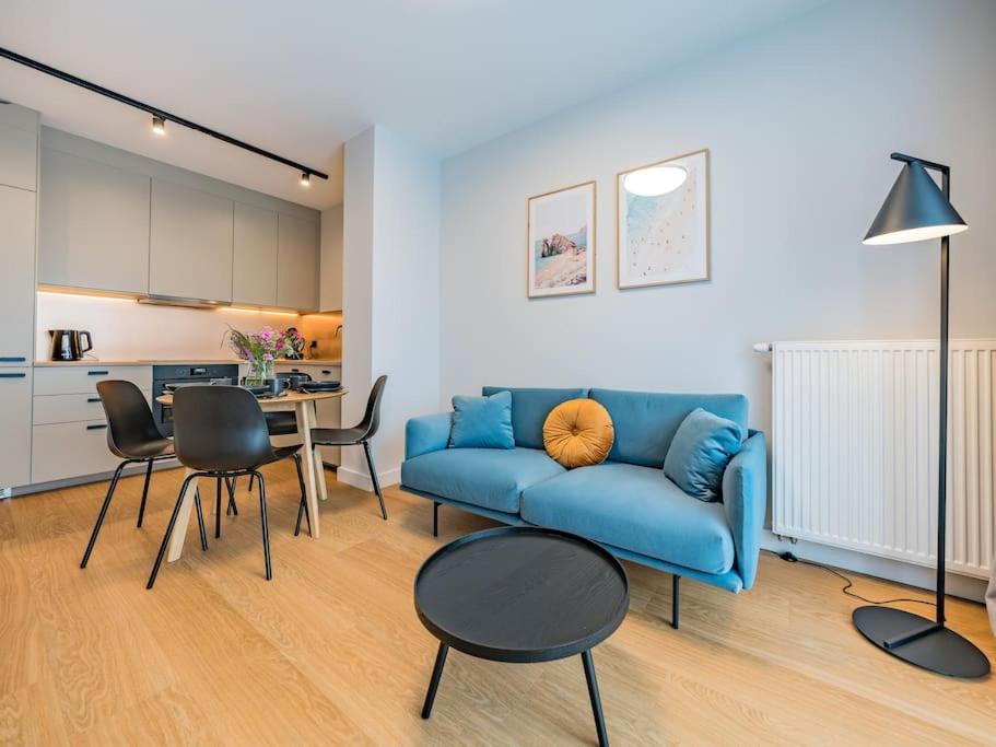 een woonkamer met een blauwe bank en een tafel bij Hello Apartments RIO with private parking in Gdańsk