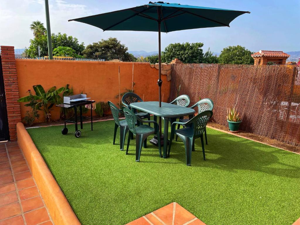 a patio with a table and chairs and an umbrella at Villa EMMA - Chalet familiar con jardín y parking en Málaga in Málaga