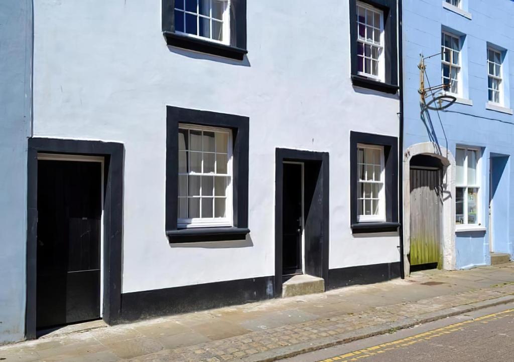 a white building with doors and windows on a street at Haven Apartments in Whitehaven