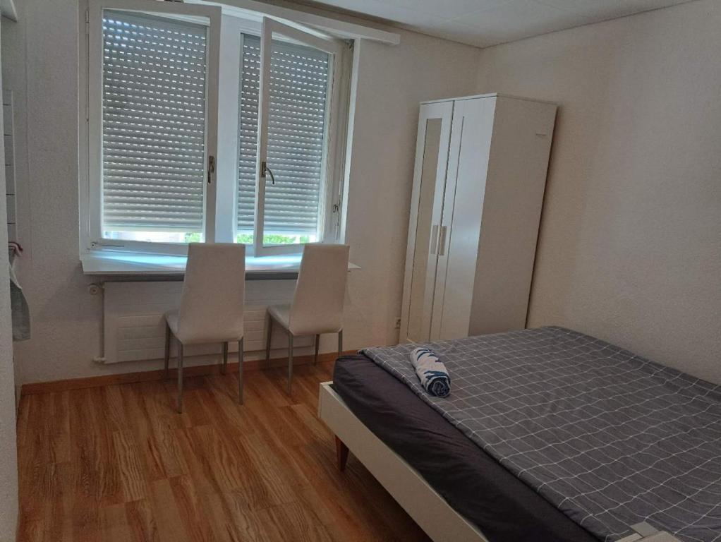 sypialnia z łóżkiem, 2 krzesłami i oknem w obiekcie City Home Zurich w Zurychu