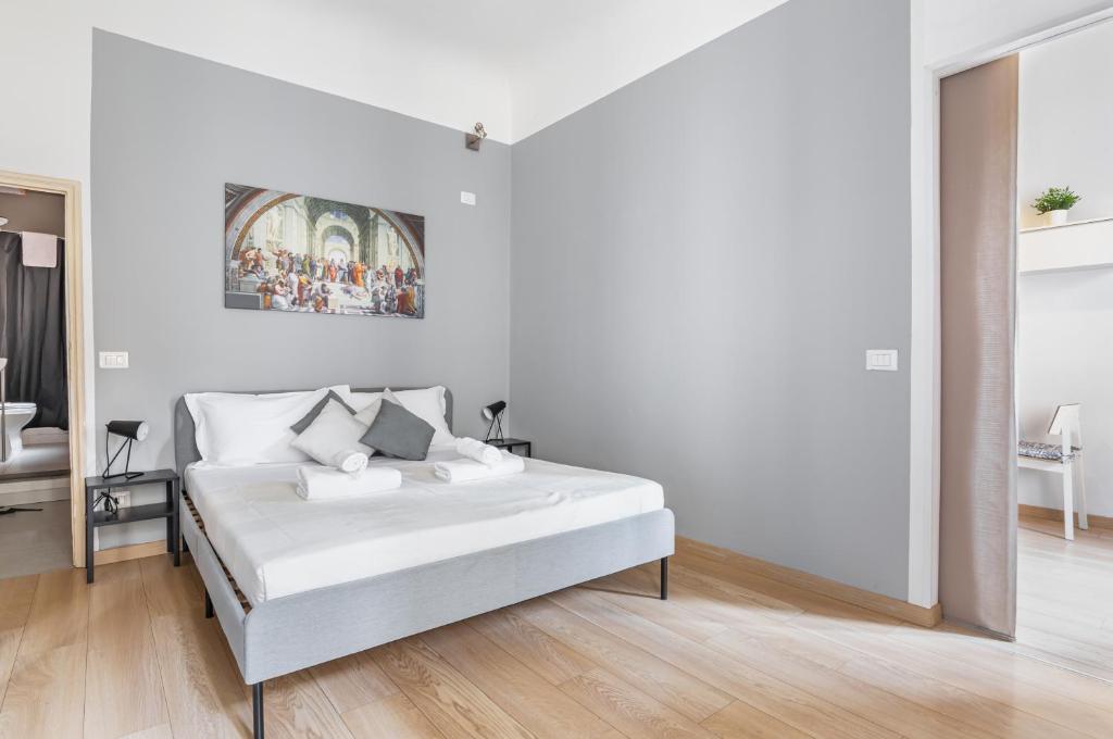 a white bedroom with a bed and a painting on the wall at Giardino della Fortezza & San Lorenzo Central Flat in Florence