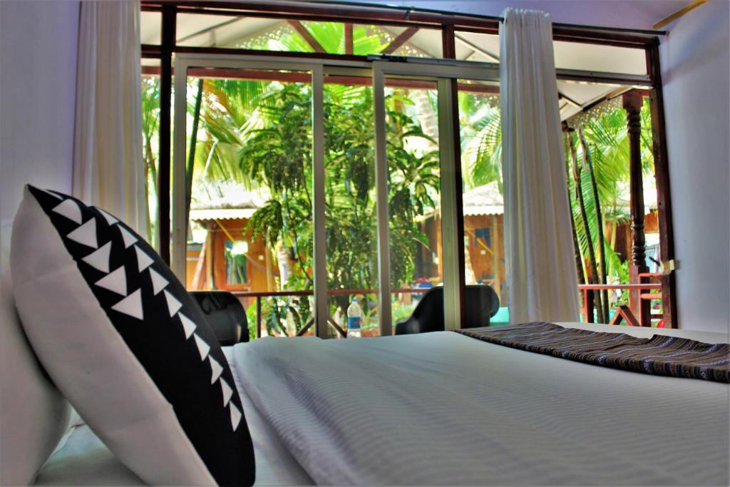 a bedroom with a bed and a large window at Sai Valentines in Canacona