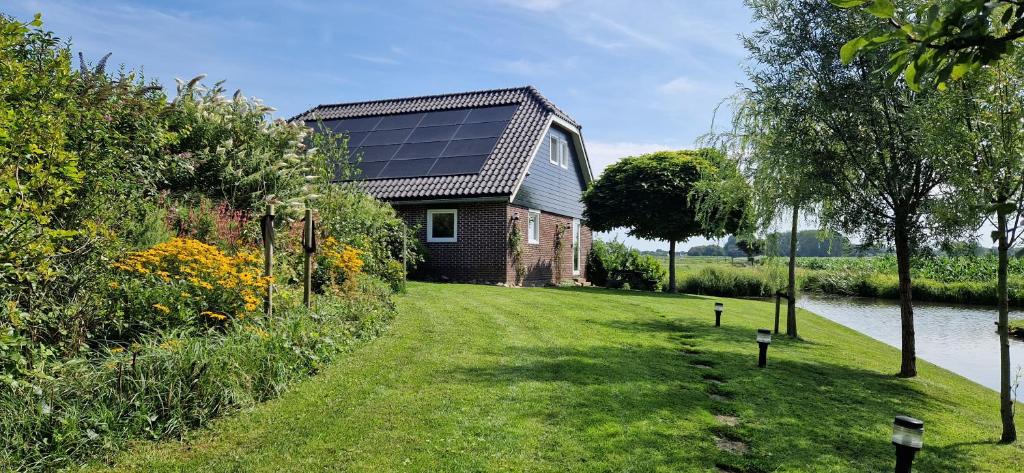 una casa con paneles solares en un lateral de un patio en Water & Meadow cottage in Central Holland 2A & 2C, en Schoonrewoerd