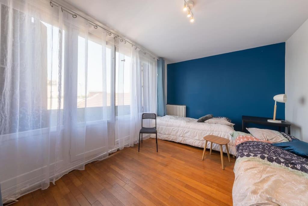 1 dormitorio con 2 camas y pared azul en Cénoslocs - Paris à vos pieds pour 6 pers., en Noisy-le-Sec