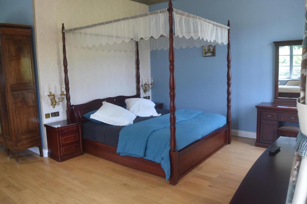 a bedroom with a four poster bed with blue sheets at Chateau Roquehort in Monein