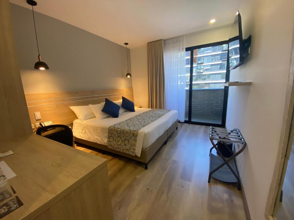 a hotel room with a bed and a large window at EcoHub Hotel Medellin in Medellín