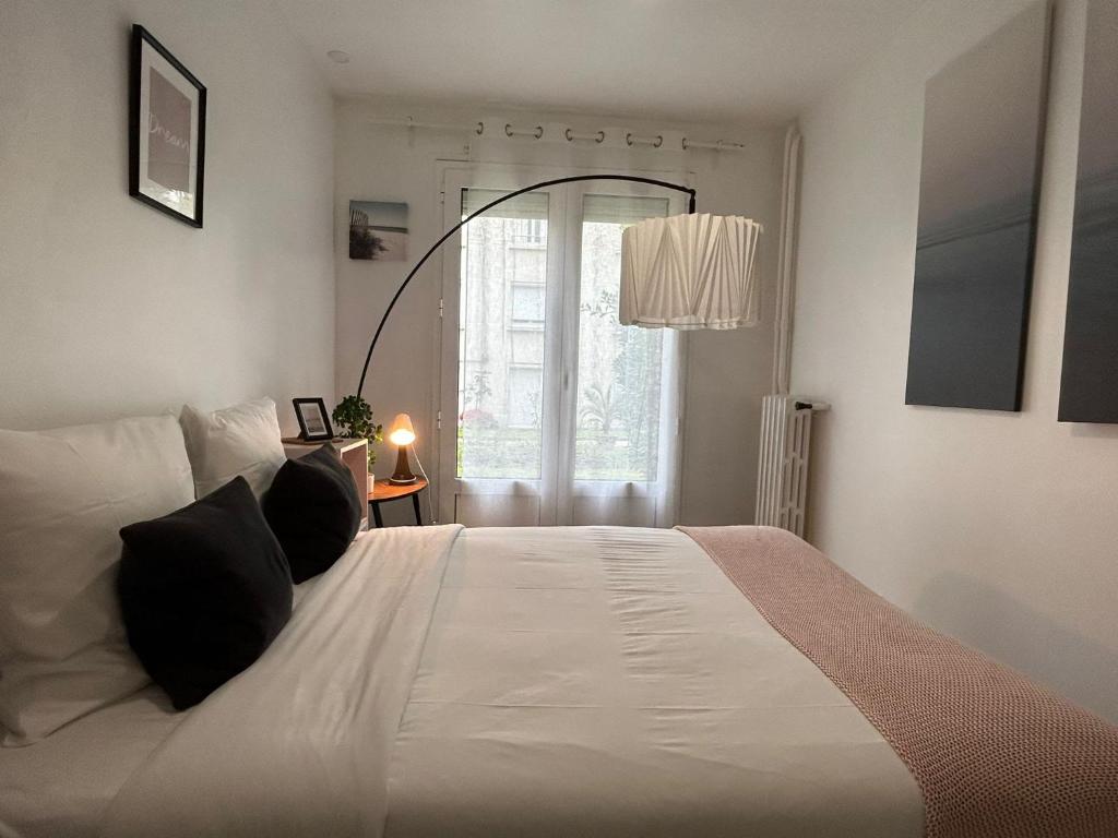 a bedroom with a large white bed with black pillows at Cosy appartement Boulogne in Boulogne-Billancourt