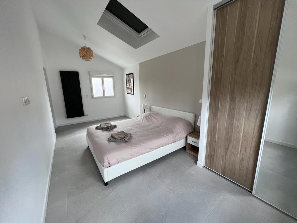 biała sypialnia z łóżkiem i lustrem w obiekcie Maison Rénovée Aux Portes Du Circuit Des 24h w mieście Mulsanne