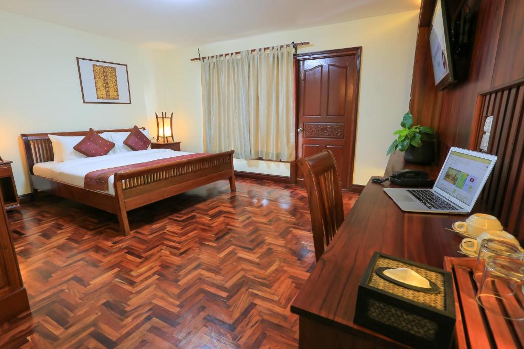 a bedroom with a bed and a desk with a laptop at Phongsavath Boutique Hotel in Vientiane