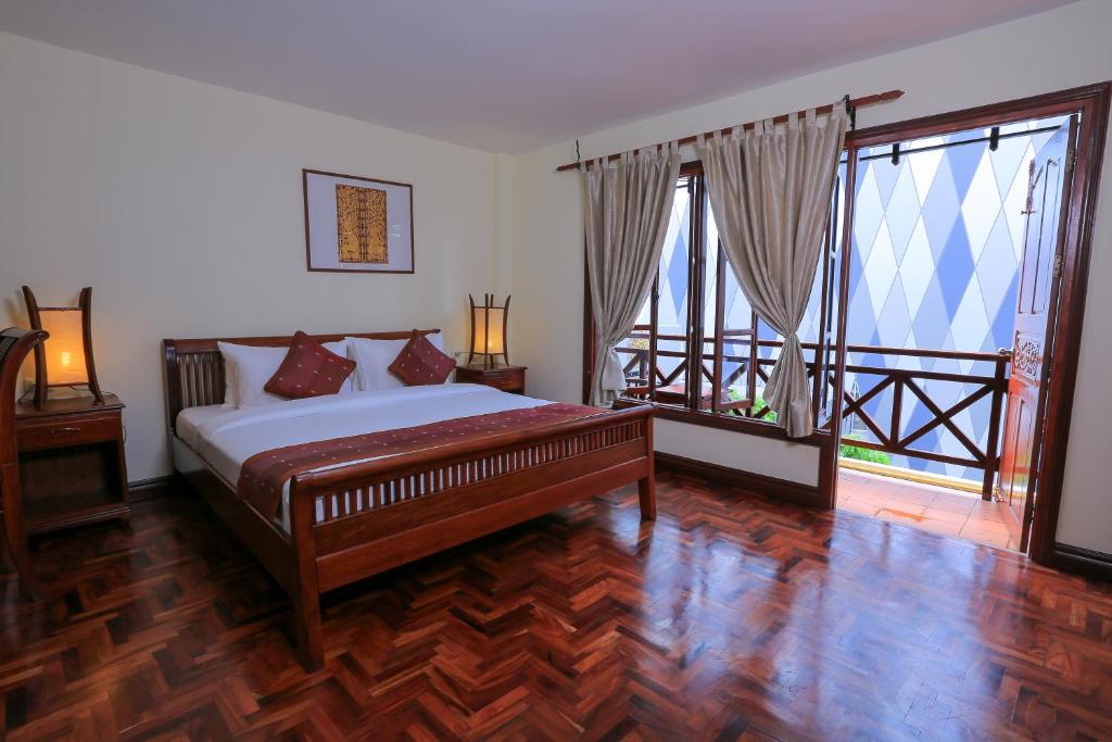 a bedroom with a bed and two large windows at Phongsavath Boutique Hotel in Vientiane