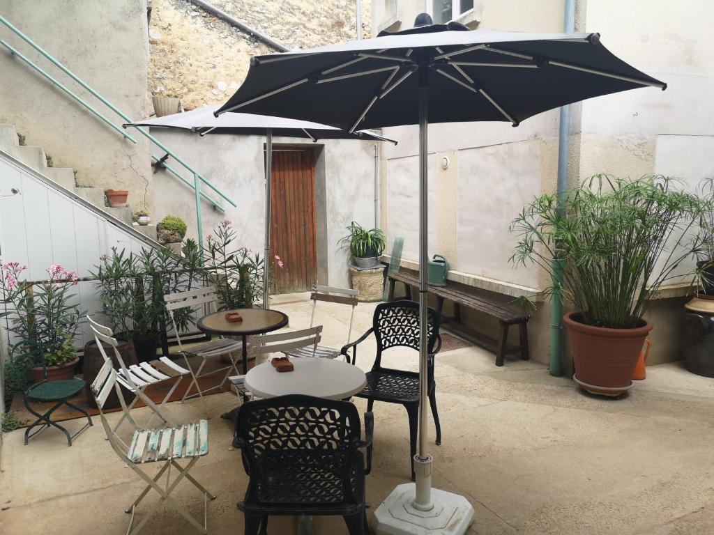 een terras met een tafel, stoelen en een parasol bij Au Terminus 15 Personnes in Hautvillers
