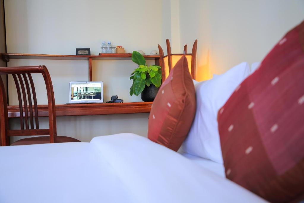 a bedroom with a bed with pillows and a plant at Phongsavath Boutique Hotel in Vientiane