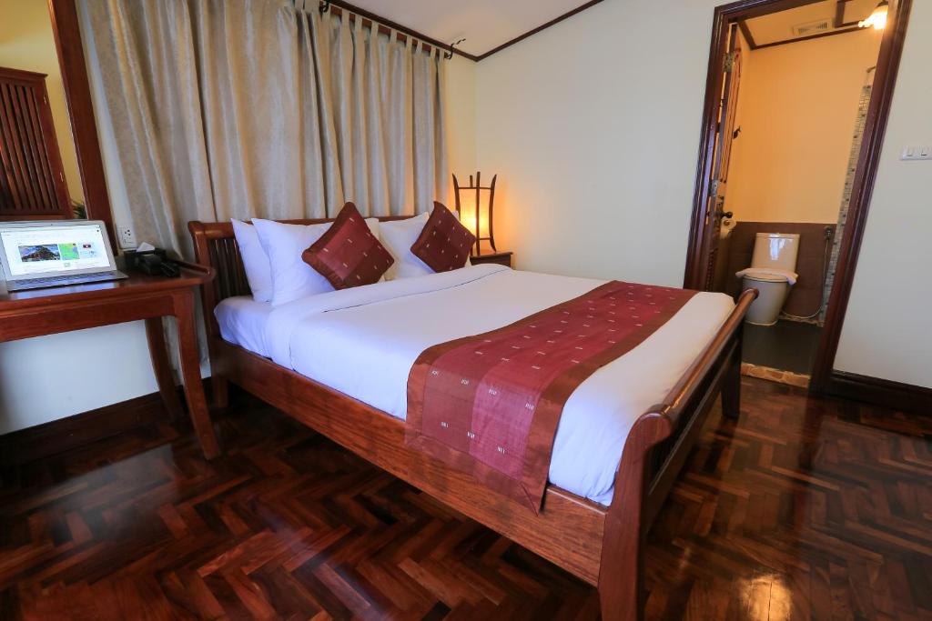 a bedroom with a large bed with a wooden floor at Phongsavath Boutique Hotel in Vientiane