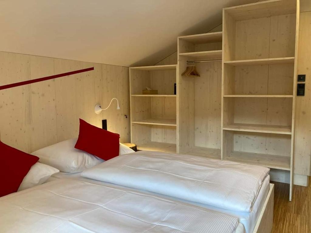 una camera da letto con letto bianco, cuscini rossi e scaffali di Horská chata Smědava a Weissbach
