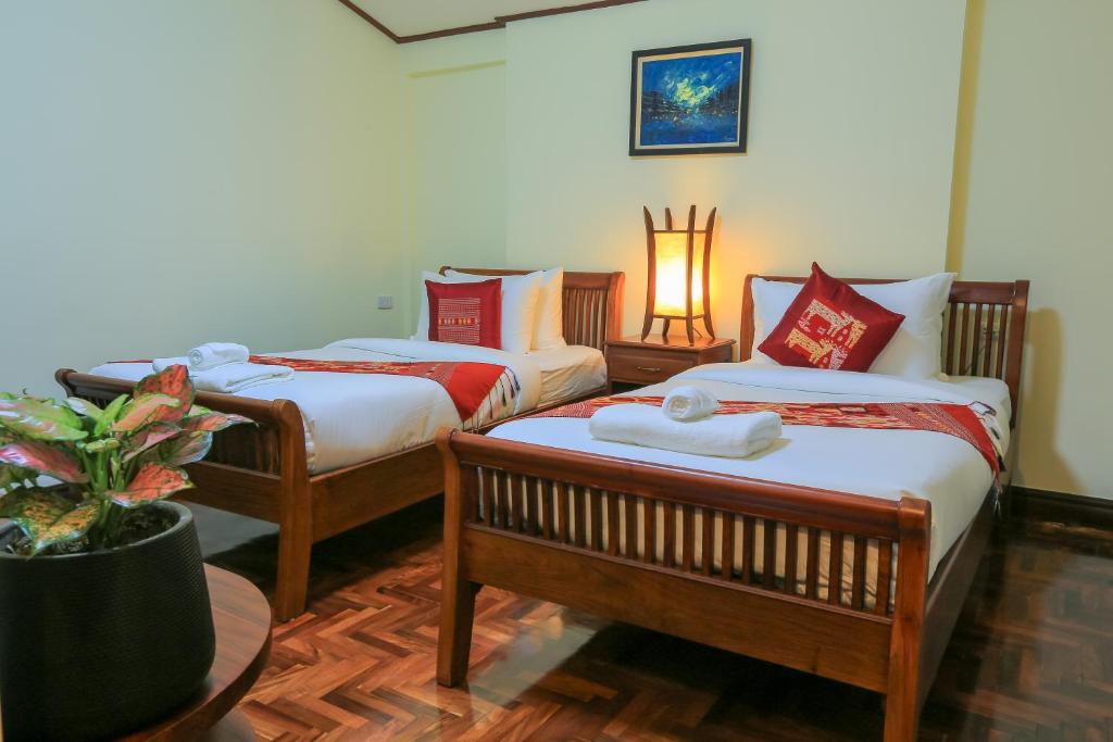 a room with three beds and a plant in it at Phongsavath Boutique Hotel in Vientiane