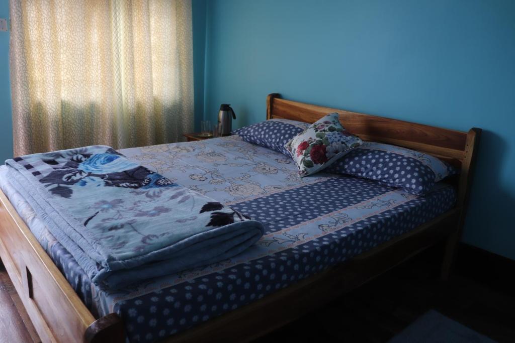 Cama en habitación con pared azul en Sparrow Nest Homestay en Darjeeling