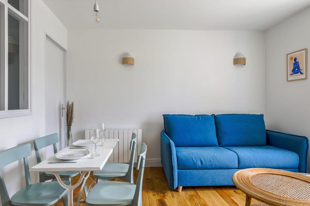 een woonkamer met een blauwe bank en een tafel bij Comfortable studio in the Grand Hôtel of Houlgate - Welkeys in Houlgate