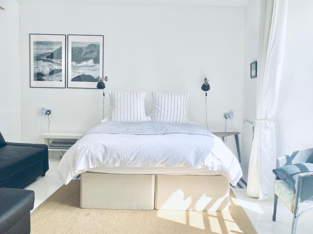 a white bedroom with a bed and a blue couch at The Art Room Apartment in Cardigan