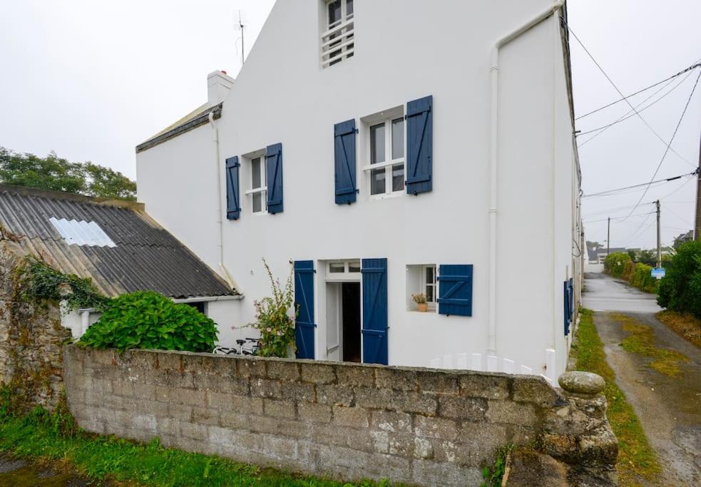 Cette maison blanche est dotée de fenêtres bleues et d'un mur en pierre. dans l'établissement Maison de vacances 5-7 personnes, à Saint-Pierre-Quiberon