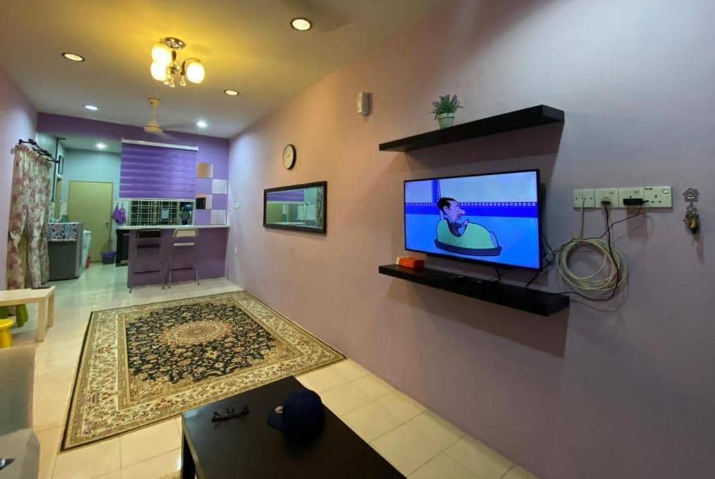 uma sala de estar com uma televisão na parede em Teratak HZ Homestay 2 em Kuantan