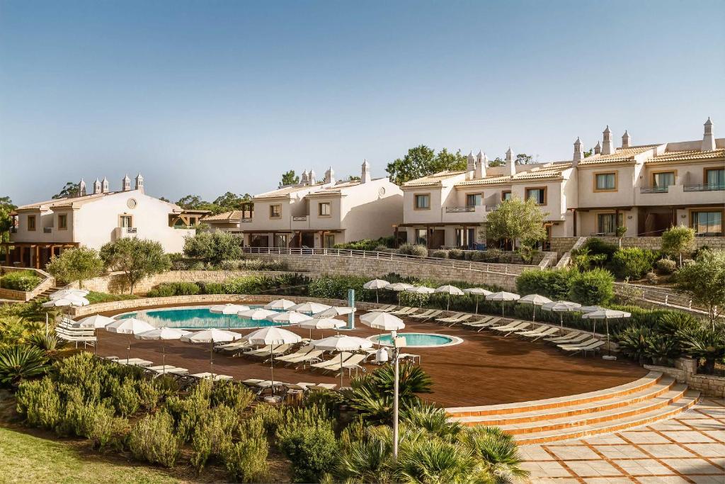 a resort with a pool and chairs and buildings at Grande Real Santa Eulalia Resort & Hotel Spa in Albufeira